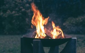 Schwarze Feuerschale mit lodernden Flammen im Freien